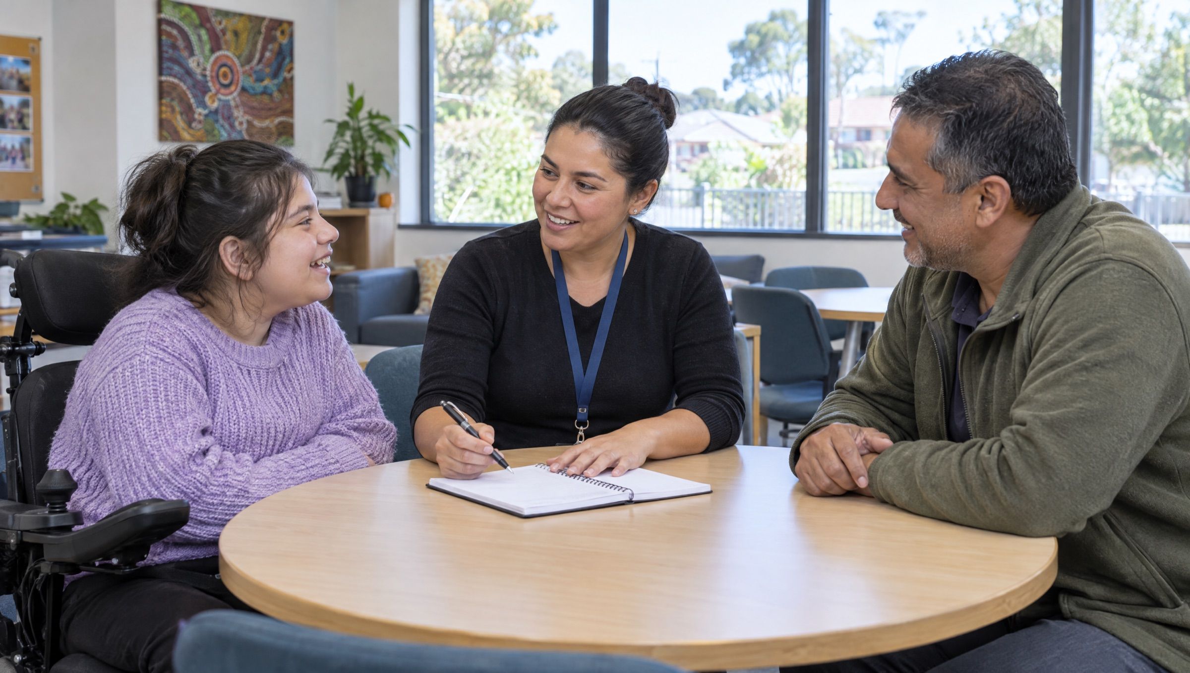A support coordinator talking through options with a young woman and her father at a round table.